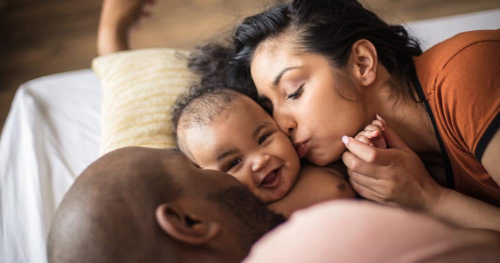 Two new parents kiss their baby on the cheeks after counseling.
