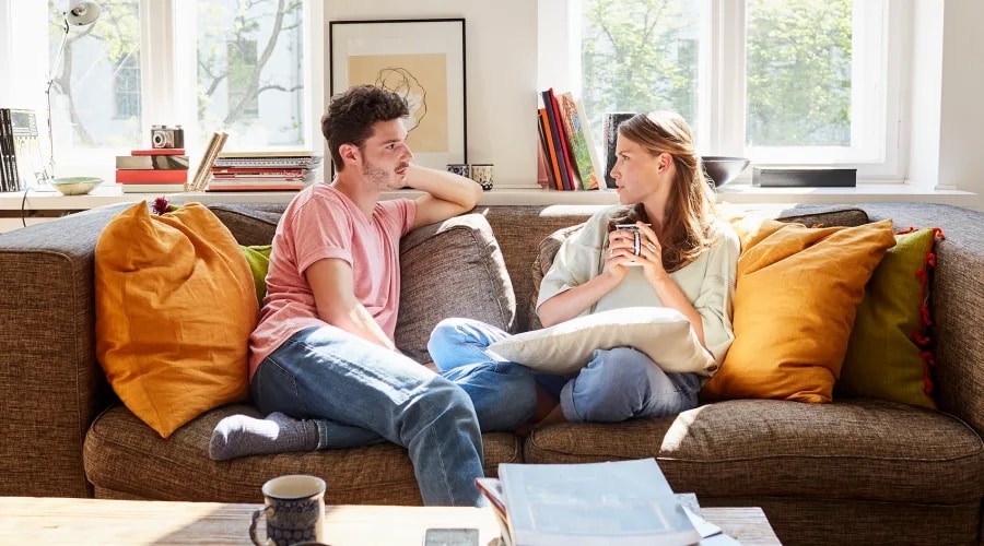Man and woman sitting on a couch talking to each other