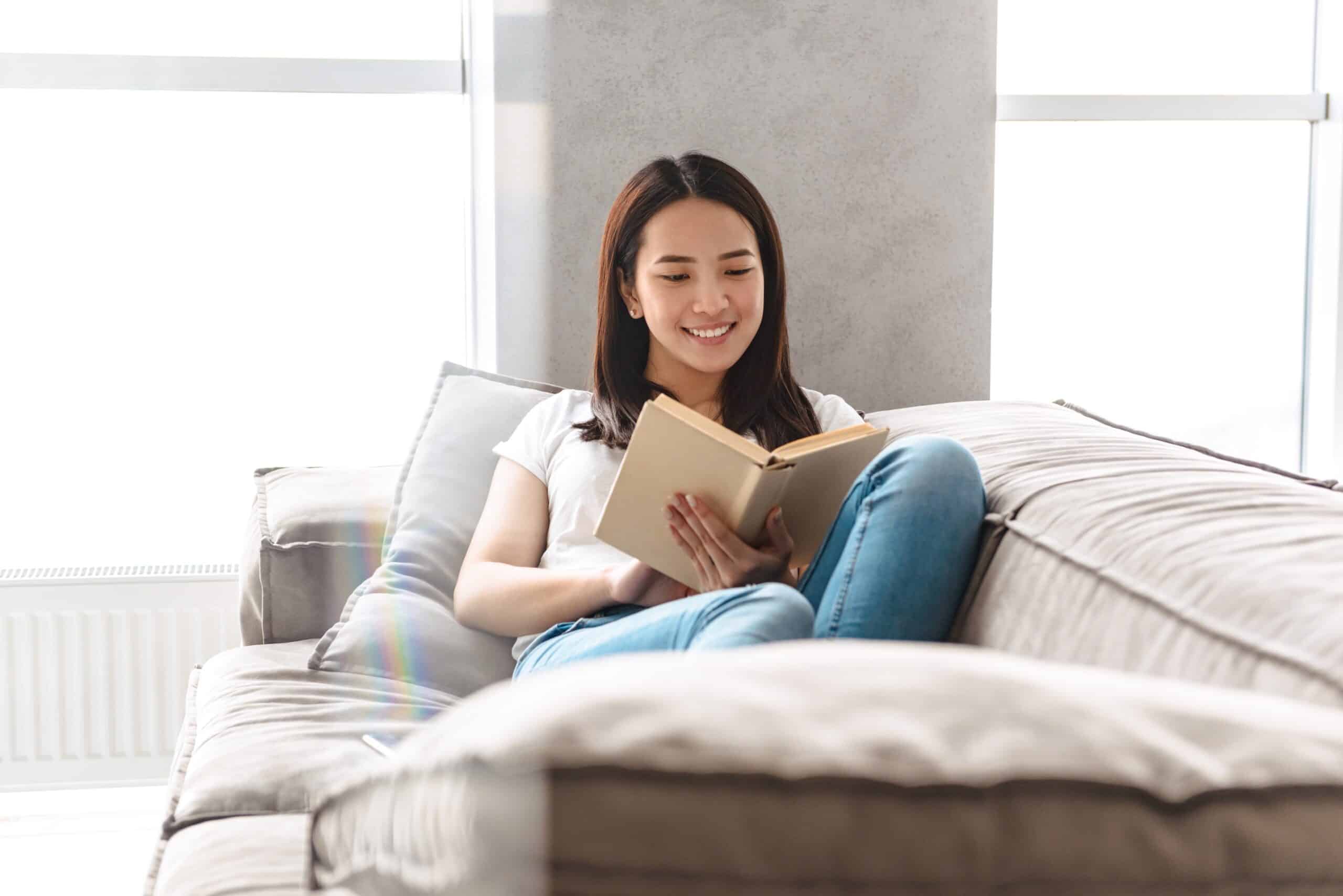 Woman sitting in bed smiling while reading a book